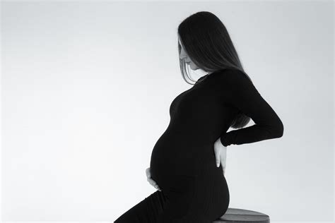 Grayscale Photo Of A Pregnant Woman Holding Belly And Her Back · Free