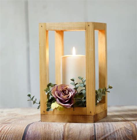 A Wooden Lantern With A Candle And Flowers In It