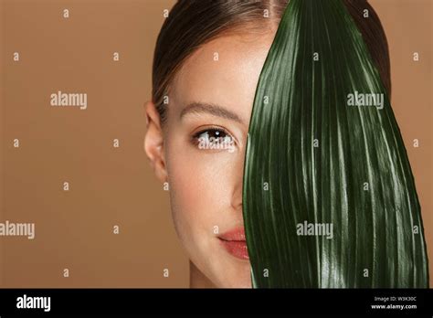 Image Of Calm Half Naked Woman Looking At Camera And Covering Her Face With Green Leaf Isolated