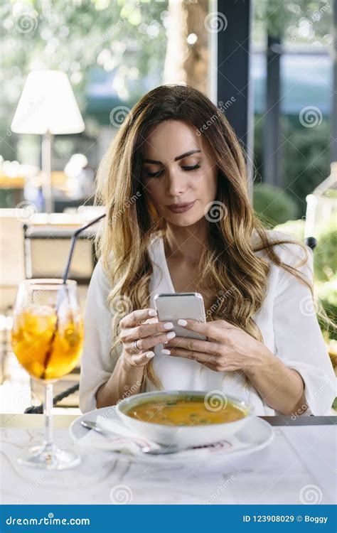 Attractive Young Woman Sitting In Restaurant And Using Mobile Ph Stock