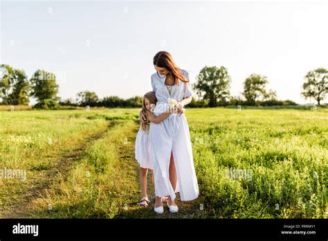 Beautiful Mother And Daughter Embracing In Green Meadow On Sunset Stock