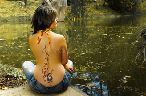 Brunette Topless Woman As Seen From Behind Sitting Down Next To Water