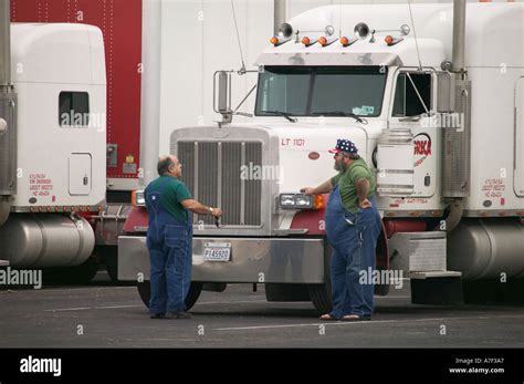 Long Haul Truck Drivers In Conversation In Front Of Trucks At Rest Stop