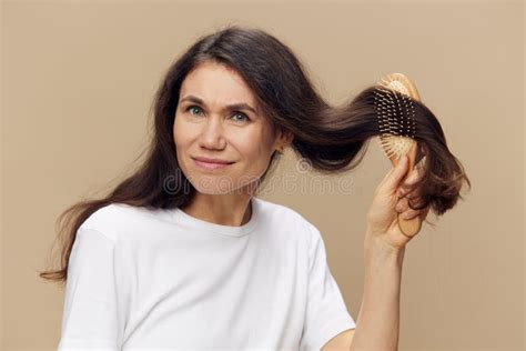 A Sweet Beautiful Middle Aged Brunette Woman Stands Pleasantly Smiling On A Beige Background