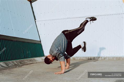 Guy Performing Handstand While Dancing Near Wall Of Modern Building On