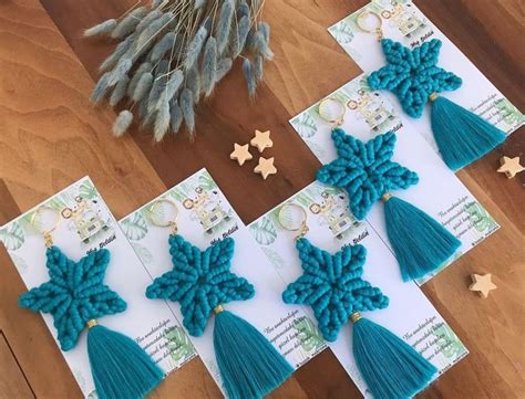 Four Pairs Of Tasseled Earrings Sitting On Top Of A Wooden Table