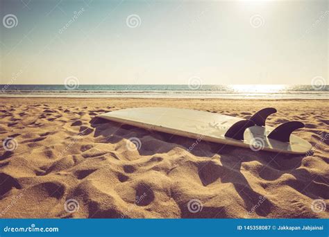 Surfboard On Sand Tropical Beach With Seascape Calm Sea And Sunset