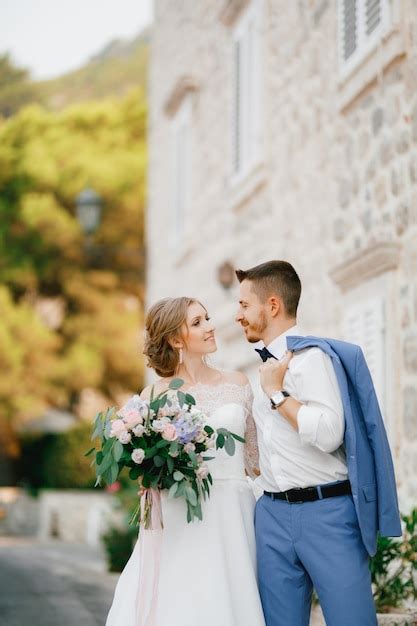 Premium Photo The Bride And Groom Stand Hugging Near A Beautiful