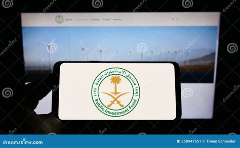 Person Holding Cellphone With Logo Of Saudi Arabian Public Investment