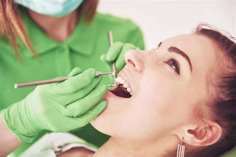 Dentista curando a una paciente femenina en la estomatología Concepto