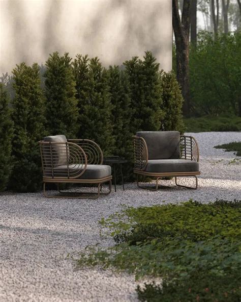 Two Chairs Sitting On Top Of A Gravel Covered Ground Next To Green