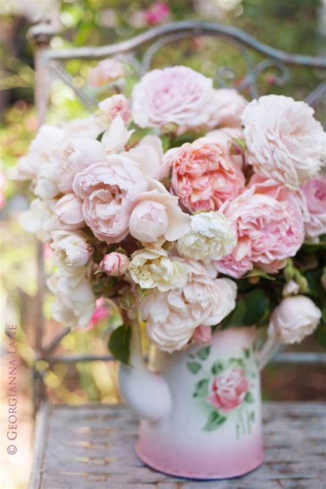 A Vase Filled With Pink And White Flowers Sitting On Top Of A Wooden Table Next To A Metal Bench