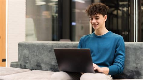 Hombre sonriente joven que trabaja con una computadora portátil en una