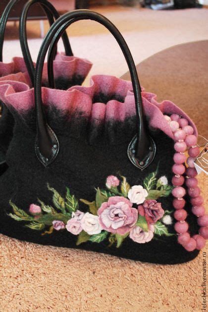 A Black Purse With Pink Flowers And Beads On The Handle Is Sitting On A