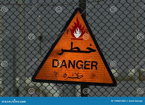 English And Arabic Danger Sign Board In Black And Orange Color Stock