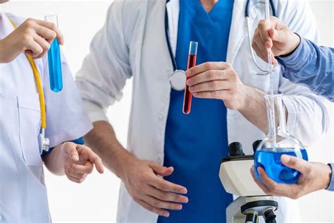 Premium Photo Midsection Of Doctors Holding Test Tube Against White