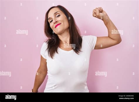 Middle Age Brunette Woman Standing Over Pink Background Stretching Back
