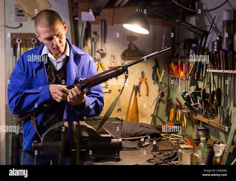 Gunsmith Examines An Automatic Rifle Before Being Repaired In Weapons