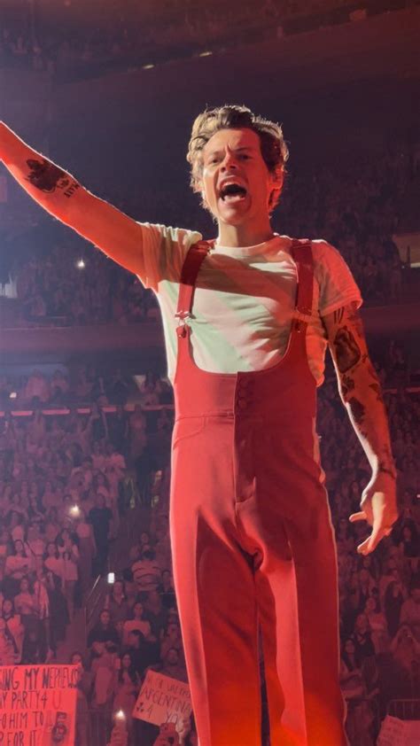 A Man In Red Overalls Standing On Stage With His Arms Out And Hands Up