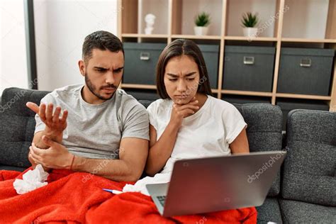 Joven pareja latina enferma que tiene teleconsulta médica usando laptop