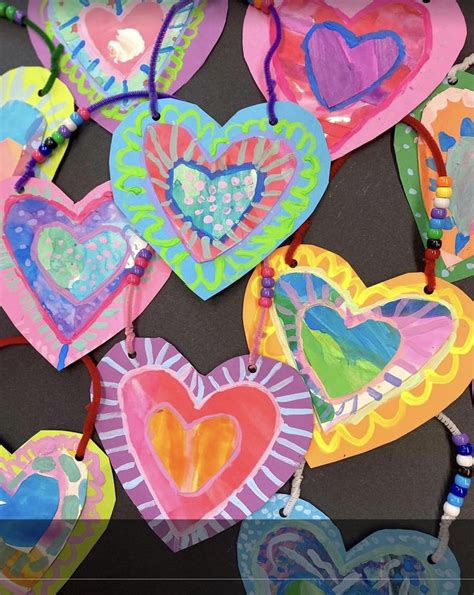 Colorful Paper Hearts Hanging From Strings On A Table