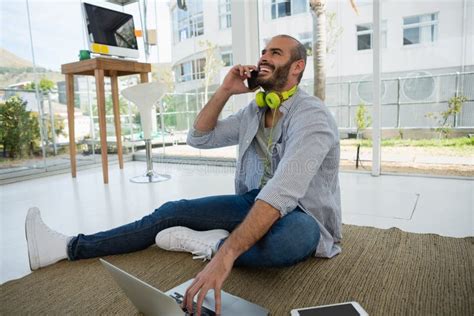 Cheerful Designer Talking on Mobile Phone while Sitting on Floor Stock ...