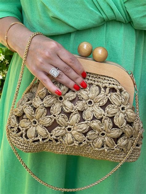 A Woman In A Green Dress Holding A Brown Purse With Gold Hardwares On It