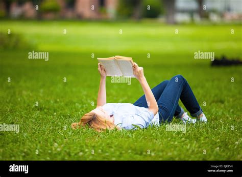 Beautiful Blonde Woman Lying In Grass And Reading A Book Stock Photo Alamy