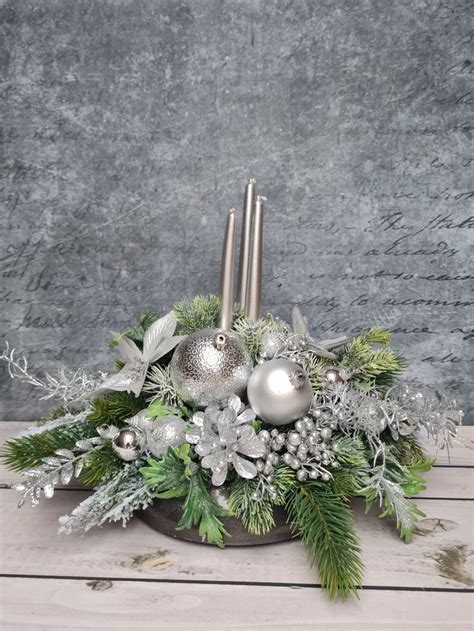 A Centerpiece With Silver Balls Greenery And Candlesticks On A Wooden