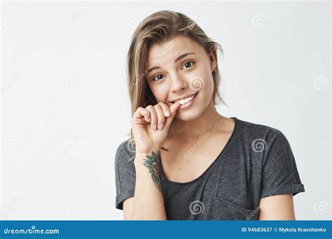 Nervous Young Pretty Girl Looking At Camera Biting Nails Over White