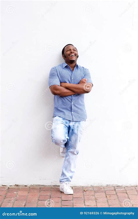 Full Body Happy Black Man Leaning Against Wall And Laughing Stock Photo