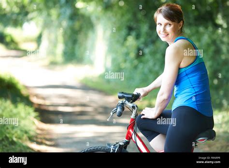 Middle Aged Woman Cycling On Country Road Stock Photo Alamy