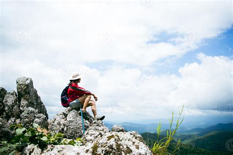 Young person hiking female sitting on top rock, Backpack woman looking ...