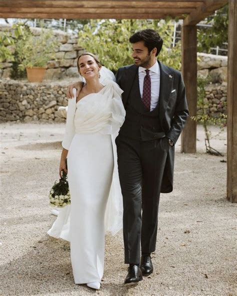 The Bride And Groom Are Walking Down The Path Together Dressed In