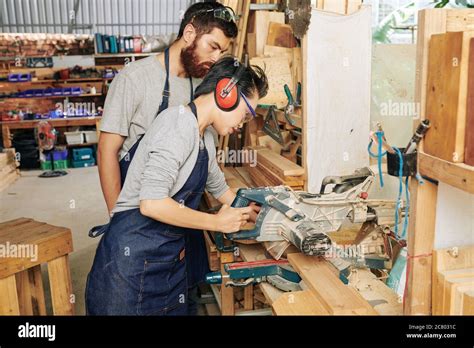 Jeune Femme Coupant Une Planche De Bois Avec Une Scie Circulaire Sous