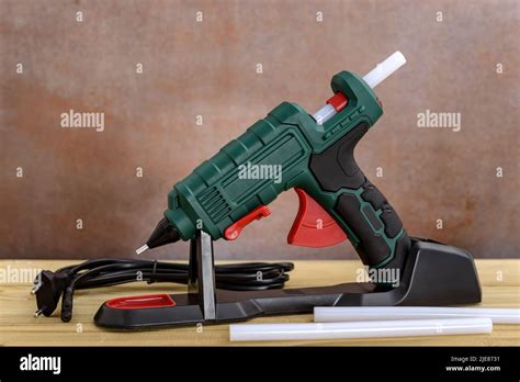 Electric Hot Glue Gun With Stand And White Glue Sticks On Wooden Background Stock Photo Alamy