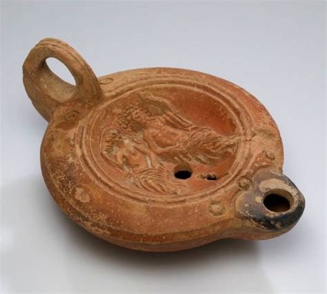 An Old Clay Object With A Bird On It S Side And A Hole In The Middle