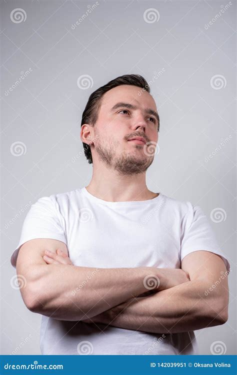 Handsome Brunette Man In A White T Shirt With Arms Crossed Is Smiling