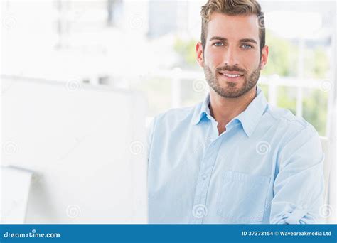 Hombre Joven Sonriente Que Usa El Ordenador En Oficina Foto De Archivo