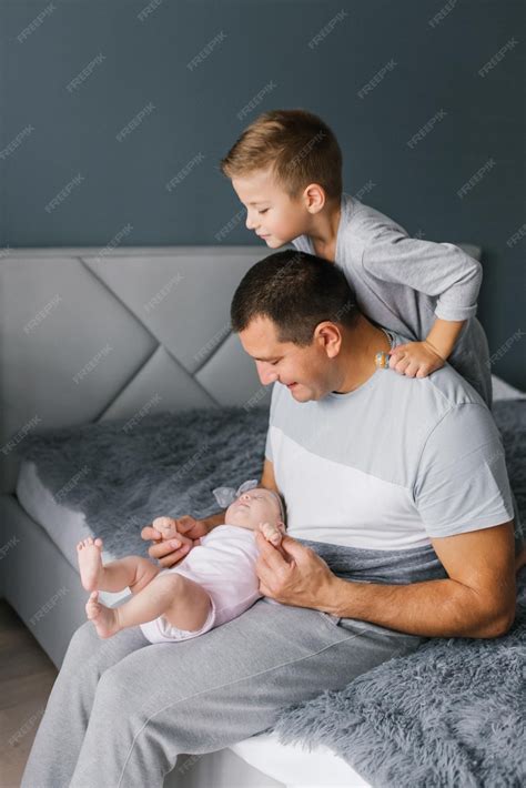 Padre Sosteniendo A Una Hija Recién Nacida La Mira En La Cama El