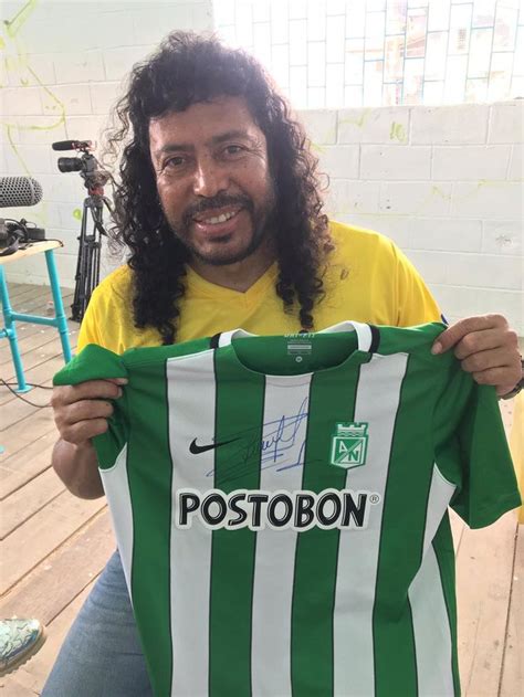 A Man With Long Hair Holding Up A Green And White Striped Shirt That