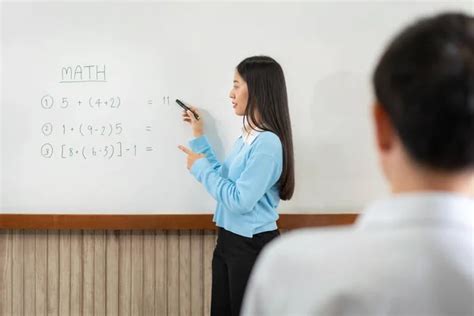 Female Tutor Standing In Front Of Whiteboard And Writing Math Equations