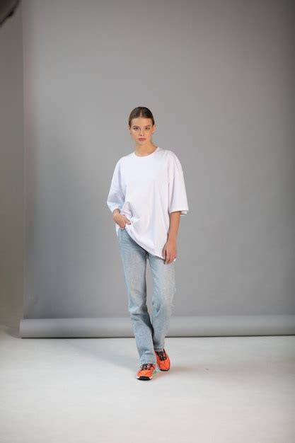 Une Belle Fille Blonde Dans Un T Shirt Blanc Surdimensionn Et Un Jean Bleu Posant Sur Un Fond