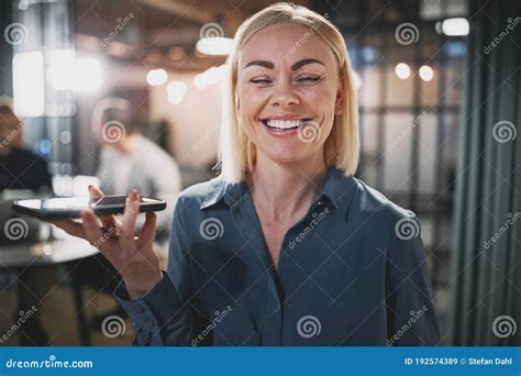 Laughing Young Businesswoman Talking On Speakerphone At Work Stock