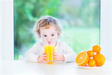 Niña Pequeña Adorable Que Bebe El Zumo De Naranja Foto de archivo