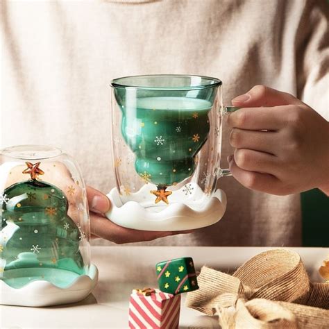 A Person Holding A Glass Cup With Christmas Decorations On It And Other