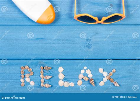 Word Relax Made Of Seashells Sunglasses And Sun Lotion On Blue Boards