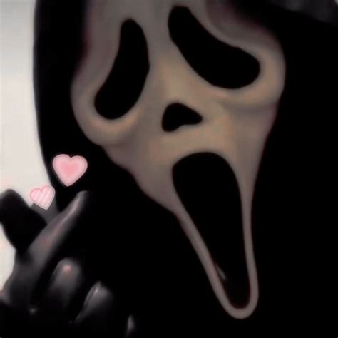 A Person In A Ghost Mask Holding A Cell Phone Up To Their Face With