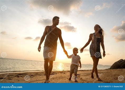 Feliz Familia Caminando Por La Playa Al Atardecer Imagen De Archivo