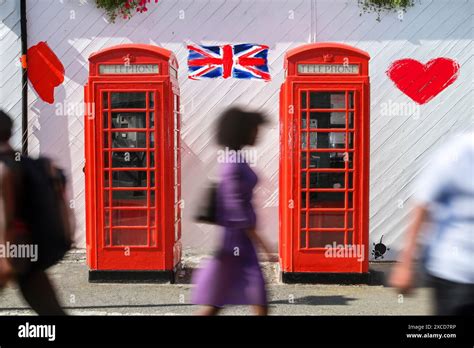 Classic Red British Telephone Booths With Blurred Pedestrians In Motion